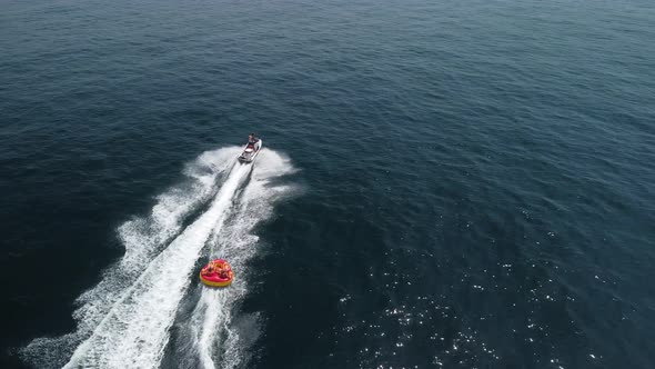 Happy People are Going to Swim on an Air Mattress Behind a Jet Ski