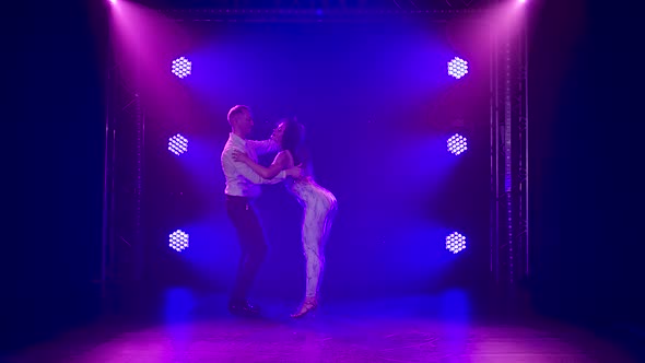 Young Couple Dancing Latin Music. Bachata, Merengue, Salsa. Shot in a Dark Studio with Neon Lights