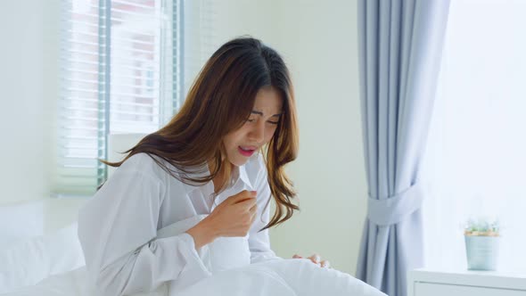 Attractive young woman feeling bad after wake up on bed and coughing in early morning at home.