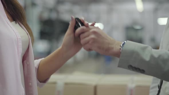 Unrecognizable Male Caucasian Salesman Giving Car Keys To Female Customer and Shaking Her Hand