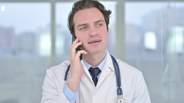 Portrait of Young Male Doctor Talking on Smartphone in Office 