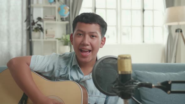 Asian Boy With Guitar Talking To Camera. The Boy Is Streaming