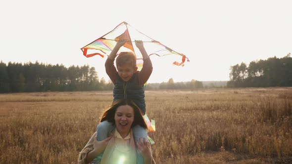 Mom and Little Son Play with a Kite in the Meadow