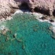 Aerial View of a Cave with Crystal Clear Waves at a Rocky Coast with Clear Blue Water - VideoHive Item for Sale