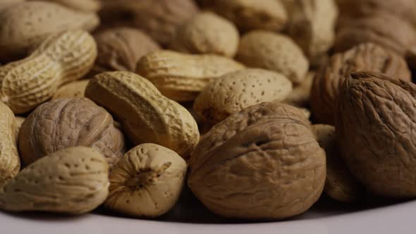 Cinematic, rotating shot of a variety of nuts on a white surface - NUTS MIXED