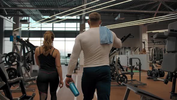 Couple of Athletes Going Through the Gym to the Exercise Machines in Slow Motion