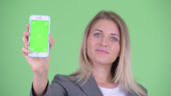 Face of Happy Young Blonde Businesswoman Showing Phone