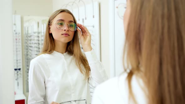 Beautiful girl wearing eyeglasses. Elegant fasionable woman choosing eyeglasses in optical store