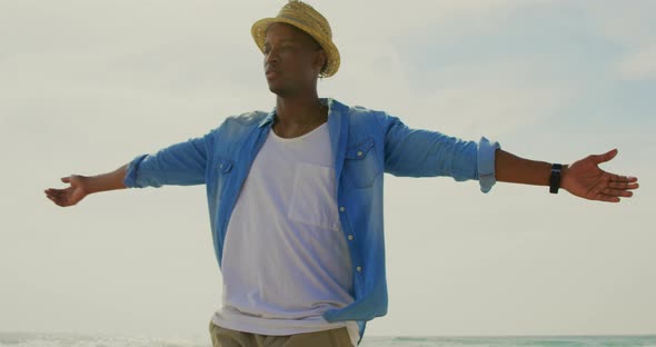 African american man spinning with arms outstretched on the beach 4k