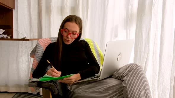 Woman Works at Home Laptop By the Window