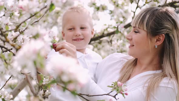 Mother and Little Son Standing Near Flowering Tree in Village