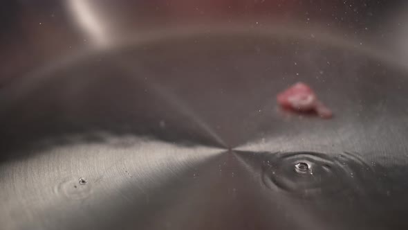 Camera follows cooking bacon in a pan. Slow Motion.