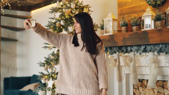 Carefree Girl Is Taking Selfie on Christmas Day Standing Near New Year Tree