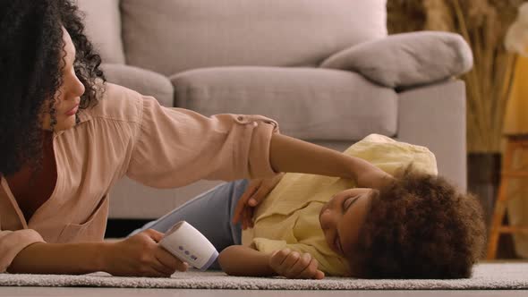 African American Woman Measures Temperature of Sick Little Girl with Non Contact Thermometer