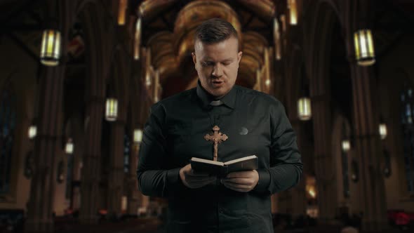 Closeup Portrait of a Young Catholic Praying Priest on the Background of the Church