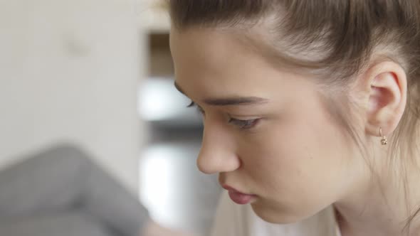 a Young Teenage Girl Makes Herself Makeup with a Small Mirror in the Bedroom