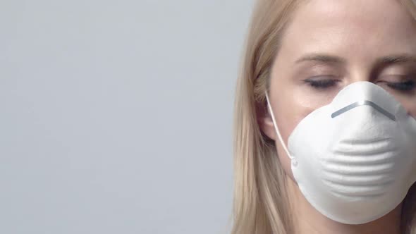 Blonde woman in protective mask on grey background