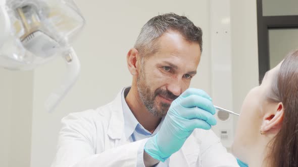 Charming Male Dentist Smiling To the Camera While Working with Patient