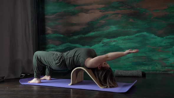 a Woman in a Green Jumpsuit is Lying on a Sports Mat