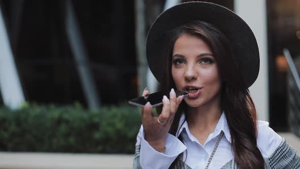 Business Lady in Black Hat Sending Audio Voice Message on Cellphone at Outdoor Talking To Mobile