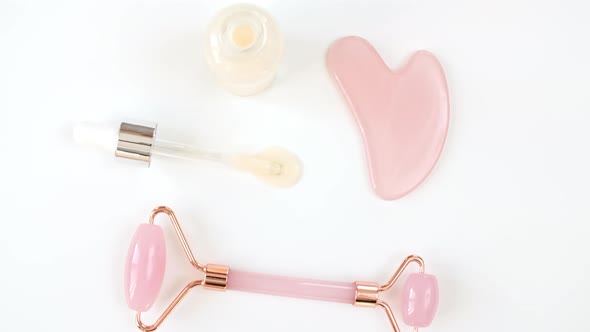 Rotation of Pink Quartz Facial Roller and Glass Bottle with Pipette with Gel Fluid Collagen Serum