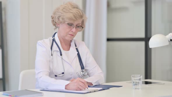 Old Female Doctor Writing on Paper Medical Report