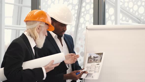 Architect and Engineer Looking at Scketch Blueprint at Office and Discussing Project