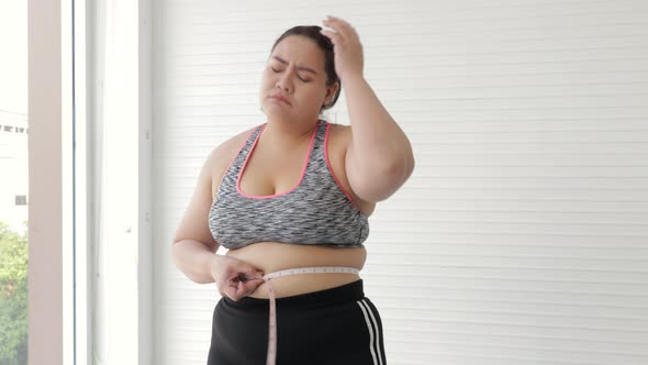 Young women are stressed about weight gain after measuring her waist with tape measure or line tape