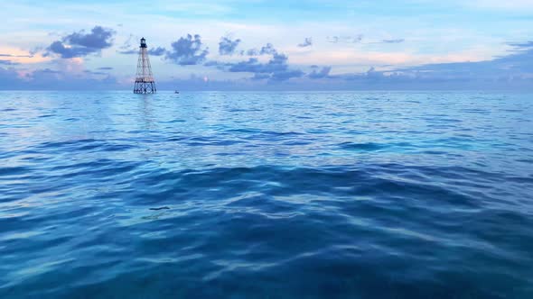 Clip of  the ocean and calm blue water witha a lighthouse in the background in Alligator Reef Light