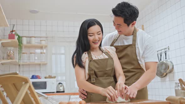 Romance Young attractive husband and wife enjoy kneaded yeast dough with hand to bake bakery.