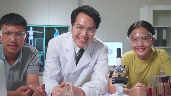 Young Asian Boy, Girl And Teacher Smiling To Camera In Classroom. Study With Scientific Equipment