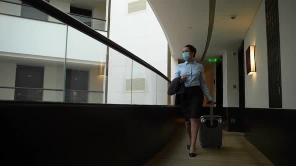 Masked Businesswoman Walking Along Hotel Corridor