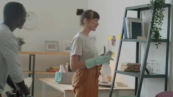 Young Multiethnic Couple Cleaning Dust and Vacuuming Home