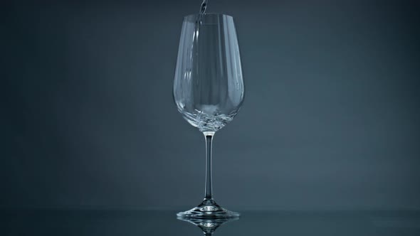 Water Pouring Wine Glass at Dark Background Closeup