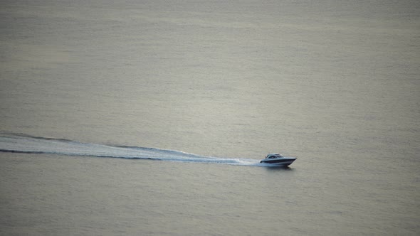 Speedboat Sailing Fast in a Calm Sea on Background of Sea Landscape with Rocky Coastline