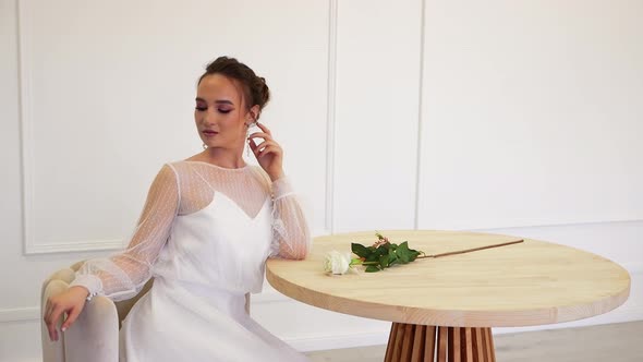 Charming Bride in a White Dress Posing for the Photographer While Sitting