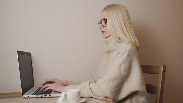 Young Good Looking Caucasian Girl Typing and Working on the Laptop Computer As Freelancer