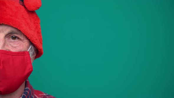 Portrait of Mature Man with Red Medical Face Mask and Santa Hat Looking at Camera