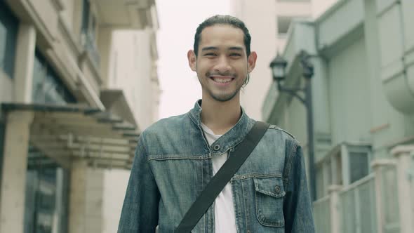 Portrait of a smiling handsome young Asian man while standing on the street in the city.