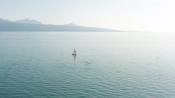 Flying towards a small sail boat on a vast, blue lake