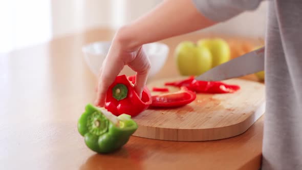 woman cutting vegetables with knife on kitchen table