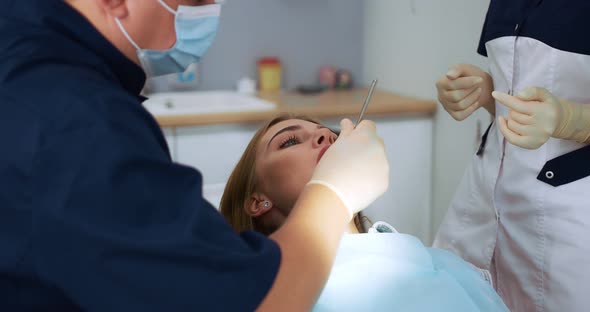 The Dentist Examines the Woman's Oral Cavity Using a Dental Mirror