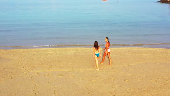 Modern happy ladies relaxing spending quality time at the beach on sunny blue and white sand backgro