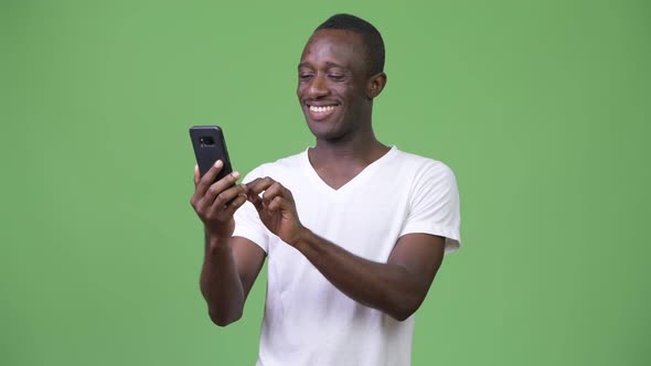 Young African Man Using Phone Against Green Background