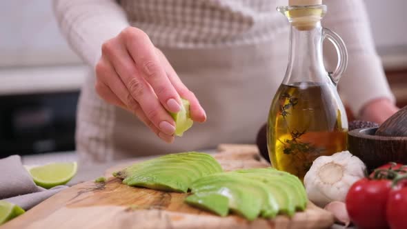 Woman Squeezing Fresh Lime Juice on a Sliced Fresh Avocado Fruit