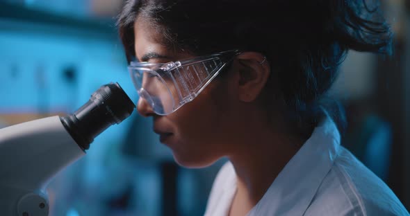 Female Research Scientist Looking Into Microscope,wearing Goggles, Close Up