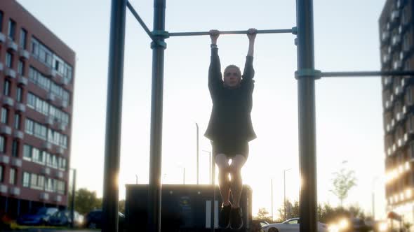 Young Woman Warms Up on Horizontal Bar in Morning in Residential Complex