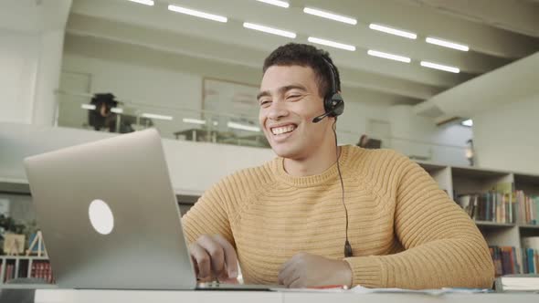 Happy Young Friendly Multi Racial Man in Eyeglasses Wearing Headset with Mic Looking at Camera