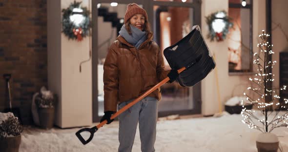 Portrait of Enthusiastic Woman with a Snow Shovel Outdoors