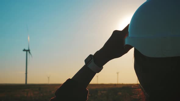 Woman Engineer Working in Wind Turbine Electricity Industrial at Sunset.